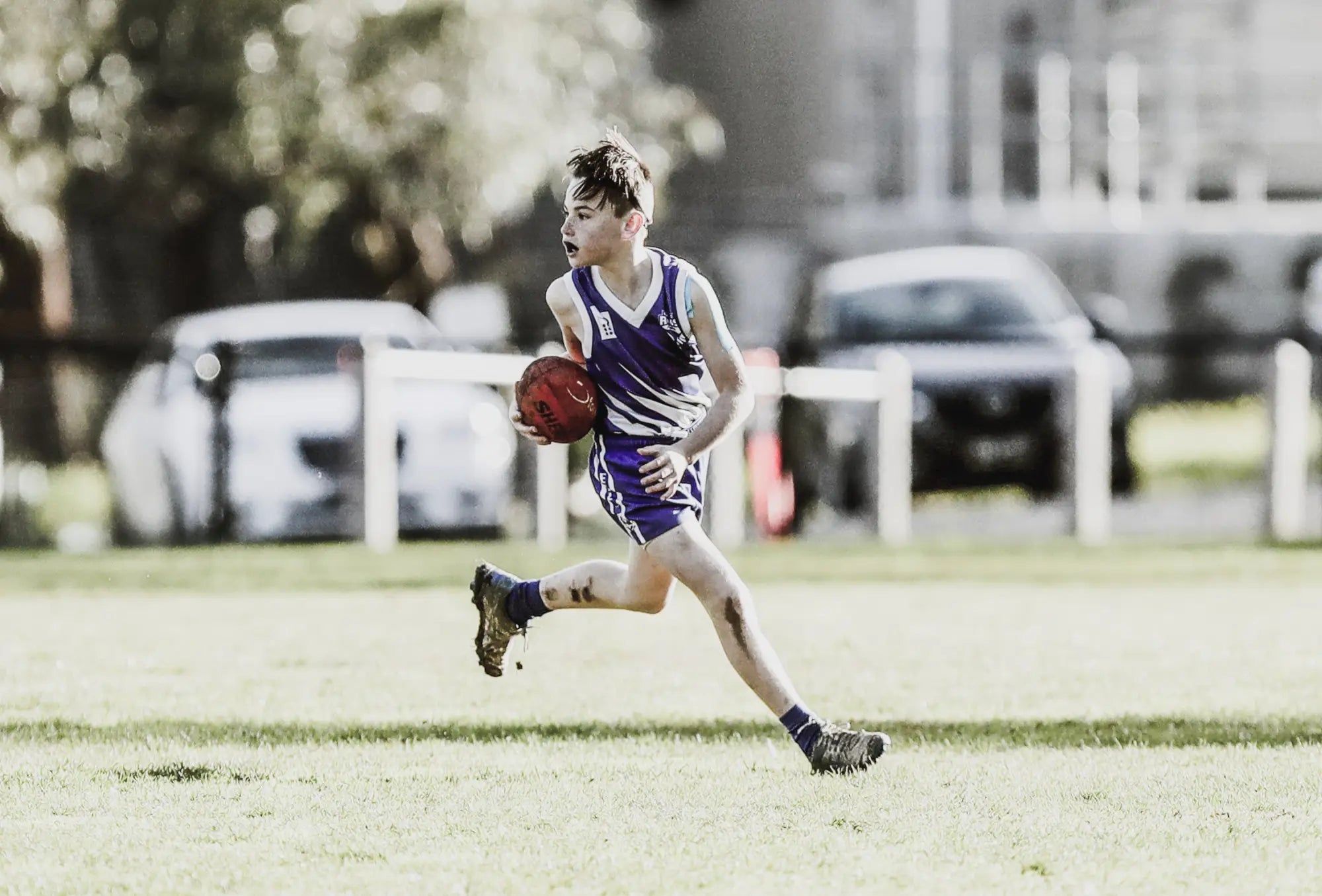 Young athlete running with a football showcasing Planett Active Range performance.
