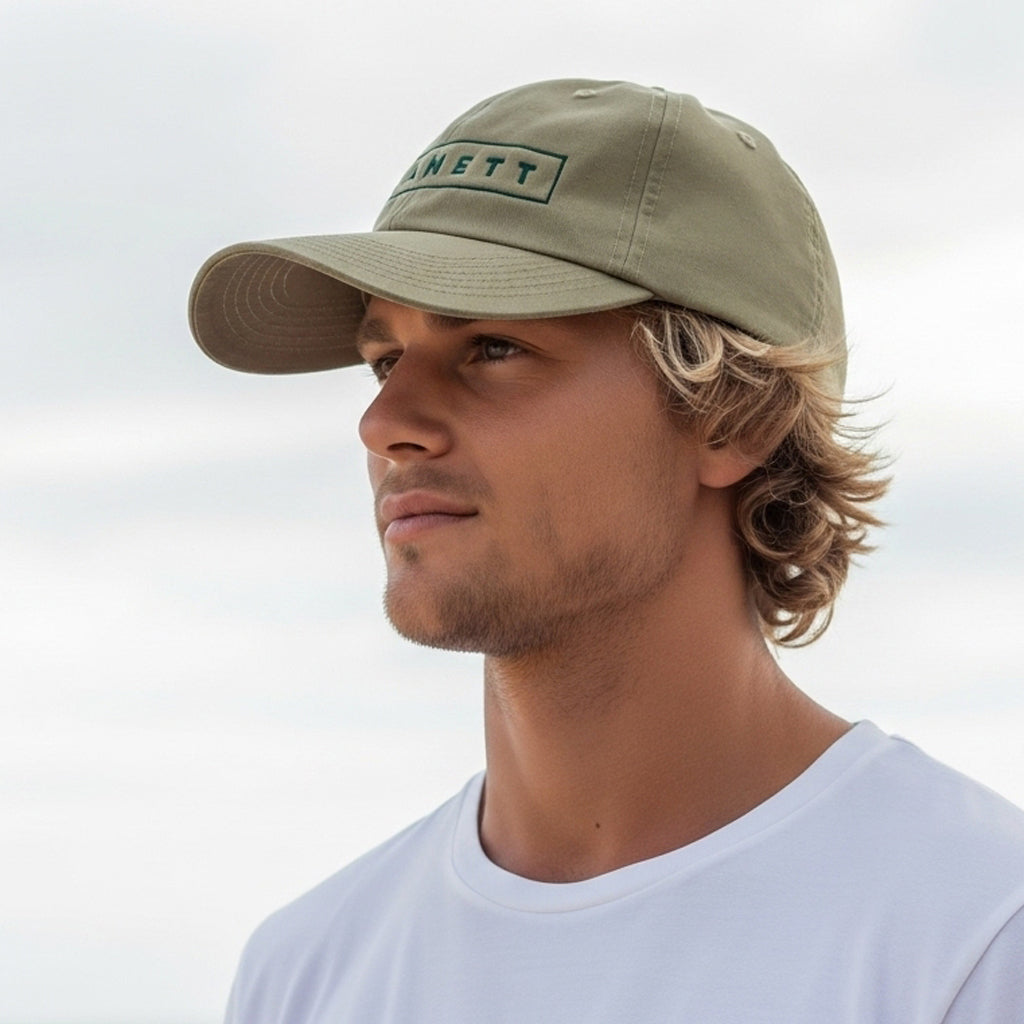 A man wearing an olive-green baseball cap with ’RANETT’ embroidered on the front.