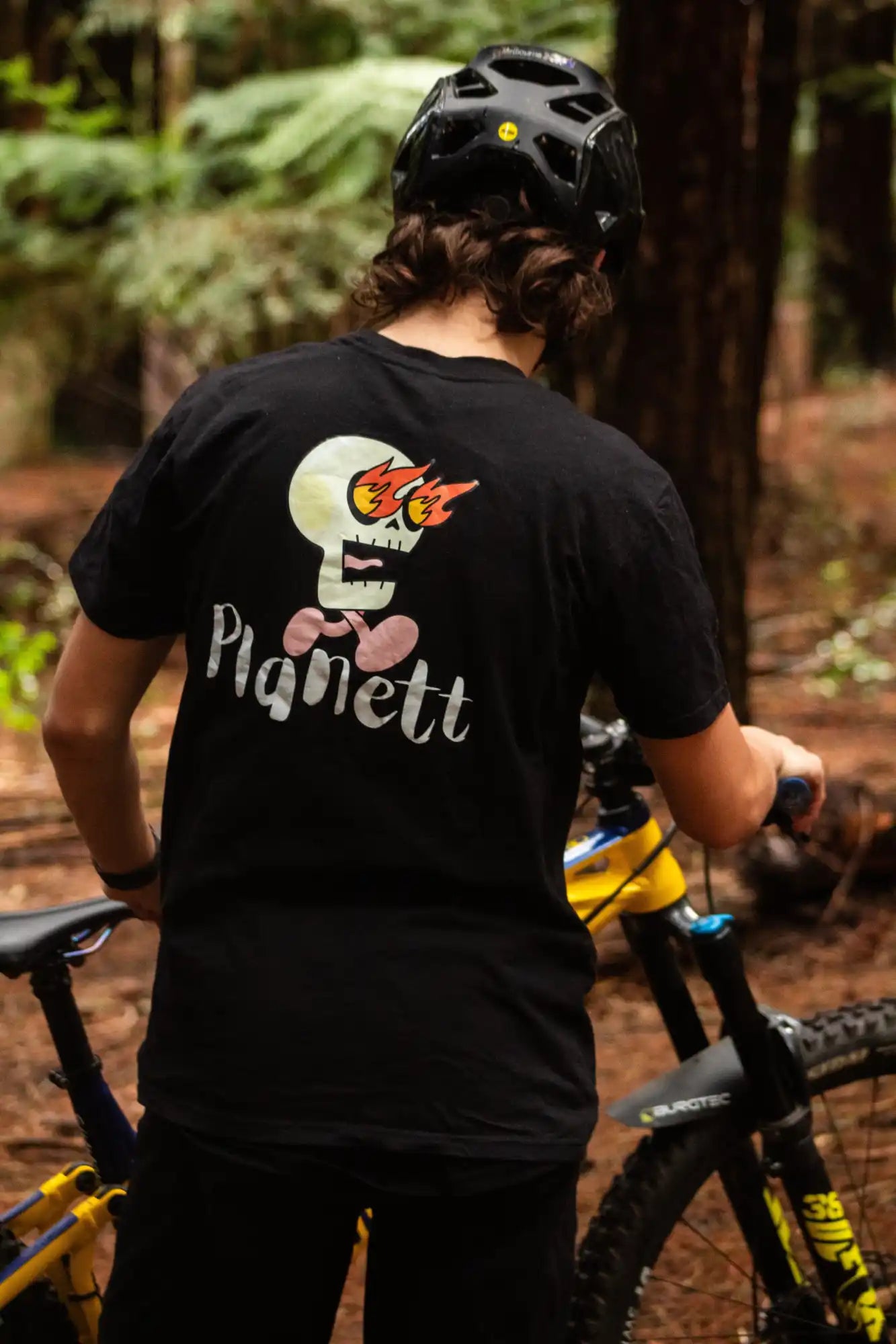 Black t-shirt with a white skull graphic with flames for eyes and a pink bow tie.