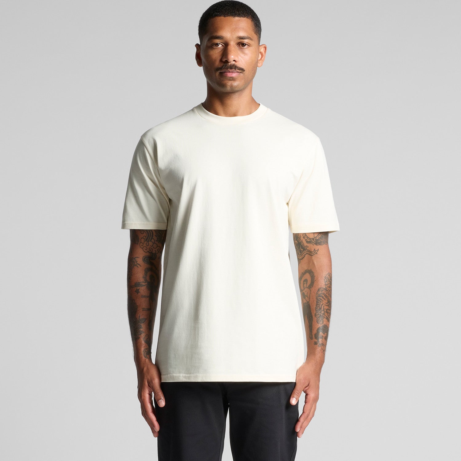 Cream-colored crew neck t-shirt with short sleeves and ribbed neckline, likely made of cotton or polyester blend.