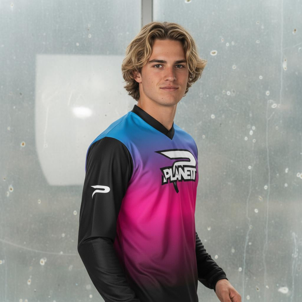 A young man with wavy blonde hair wearing a long-sleeved athletic jersey that is black on the arms and transitions from blue to pink on the torso.