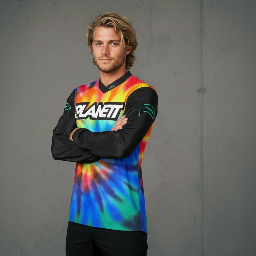 A man wearing a long-sleeved, brightly tie-dyed cycling jersey with black sleeves.