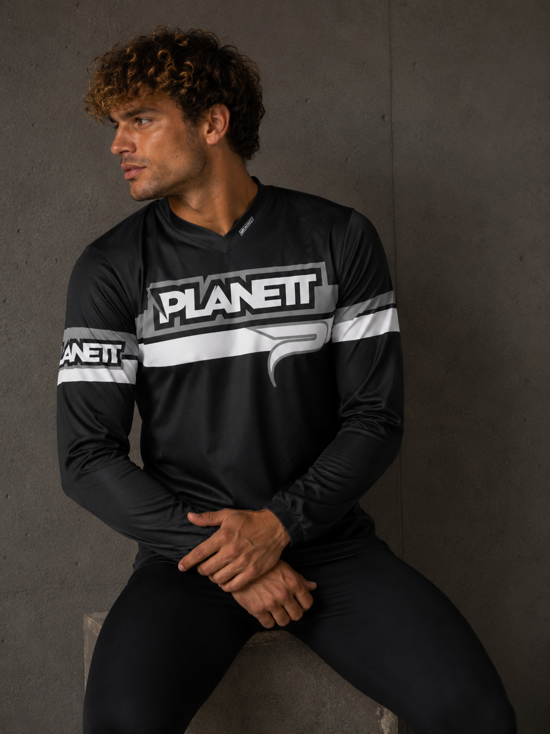 Man wearing a black sports jersey with 'PLANET' branding against a gray background