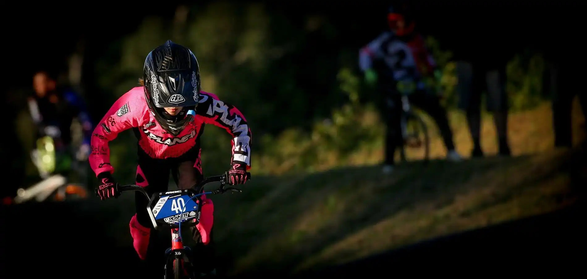 A person in full pink and black motocross gear on a bike with the number 40.