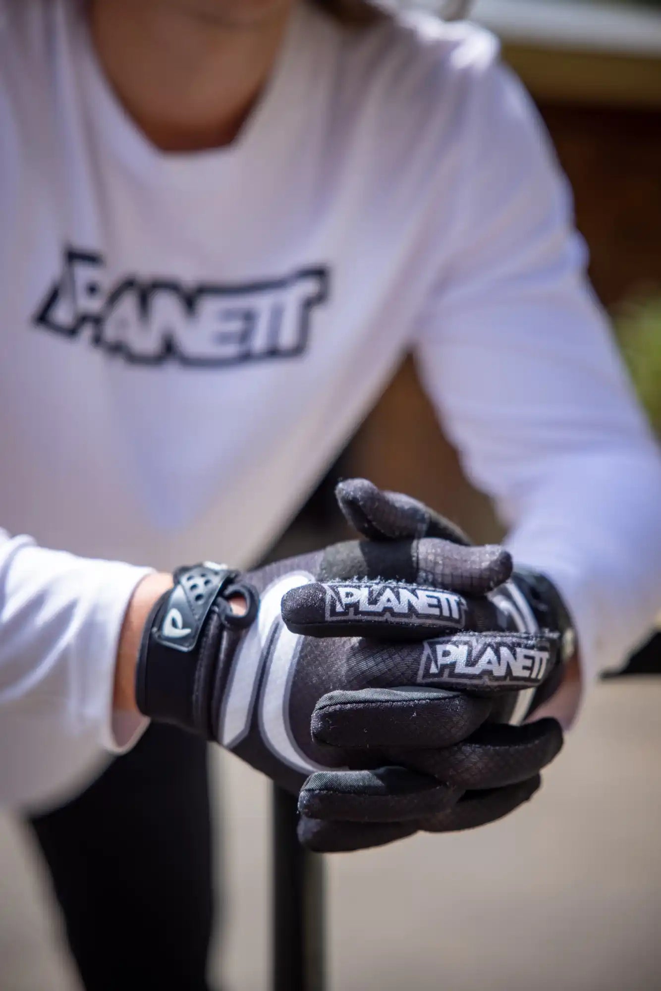 A person wearing a white long-sleeved shirt and black and white gloves.