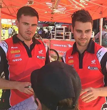 Red and black racing team polo shirts with white accents, featuring sponsor logos like motul, iveco, and honda.