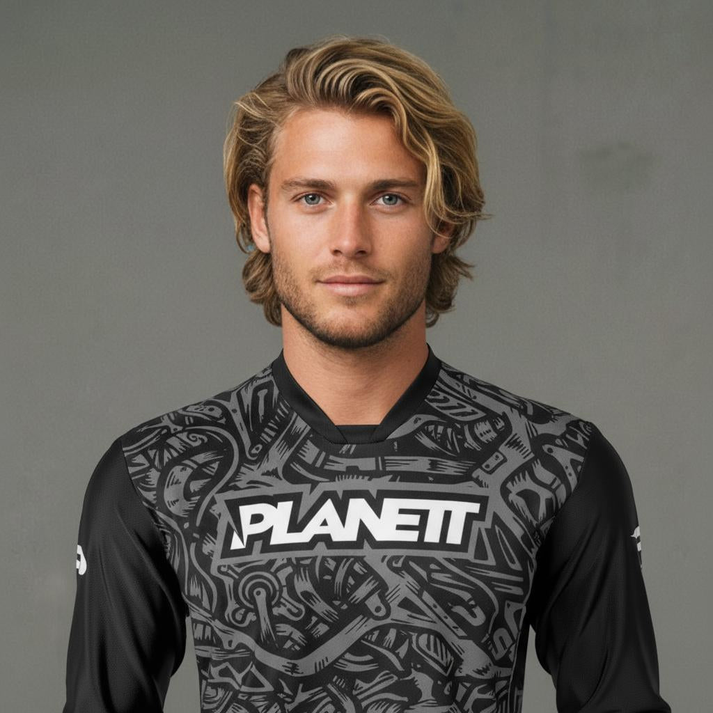 Man with blonde hair and light stubble wearing a grey and black long-sleeved shirt.