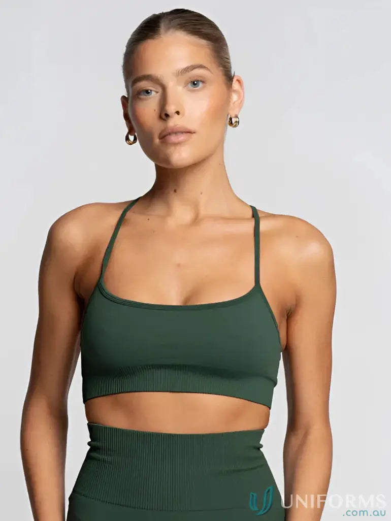 Green ribbed knit sports bra with thin straps and gold hoop earrings.