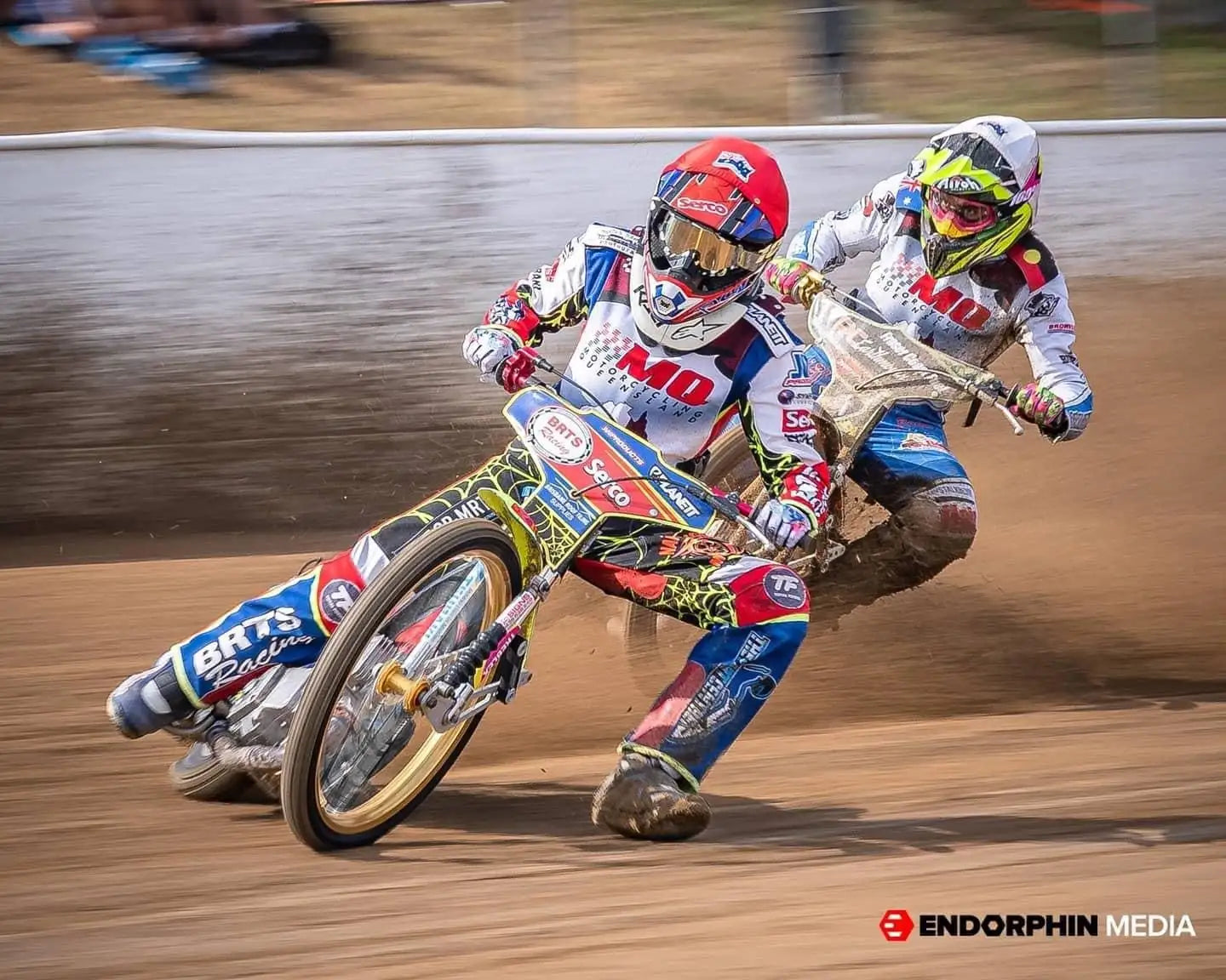 A vibrant, multi-colored speedway motorcycle with sponsor decals and a gold-rimmed front wheel.