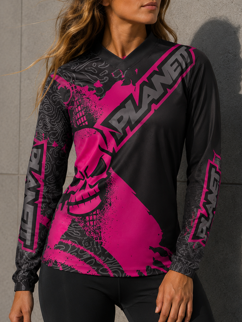 Woman wearing a black and pink 'Planet' long-sleeve shirt against a gray wall.