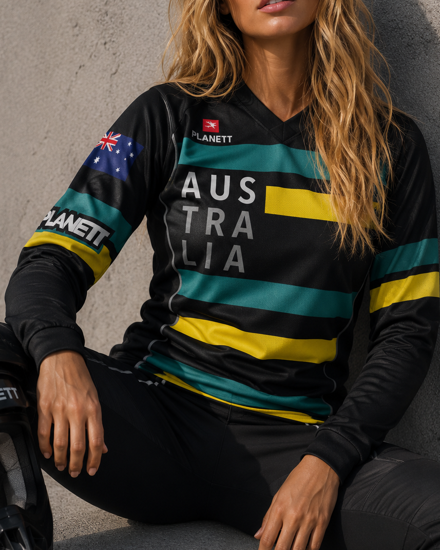 Woman wearing a sports jersey with 'Australia' text and Australian flag, sitting against a concrete wall.
