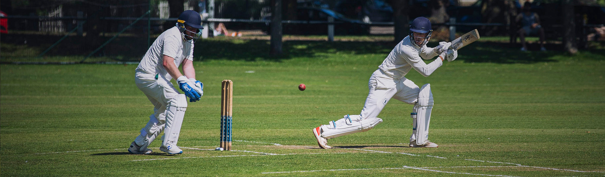 Two cricket players in action on a field.