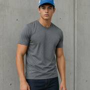 A man wearing a heather gray crewneck t-shirt and a blue baseball cap with 'PLANETS' printed on it, standing against a textured gray concrete wall.