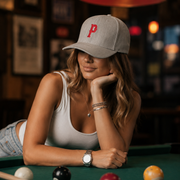 Woman wearing a cap with a 'P' logo in a pool hall setting