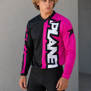 Person wearing a black and pink jersey with 'Planet' branding against a gray wall.
