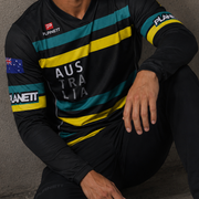 Man wearing a sports jersey with Australia branding against a concrete wall.