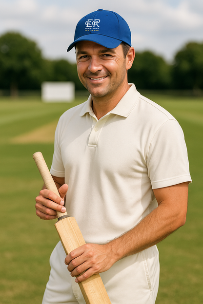 A man in a polo shirt and hat holding a cricket bat.
