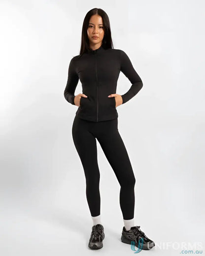 Black zip-up athletic jacket with leggings and sneakers.