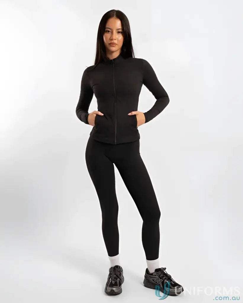 Black zip-up athletic jacket with leggings and sneakers.