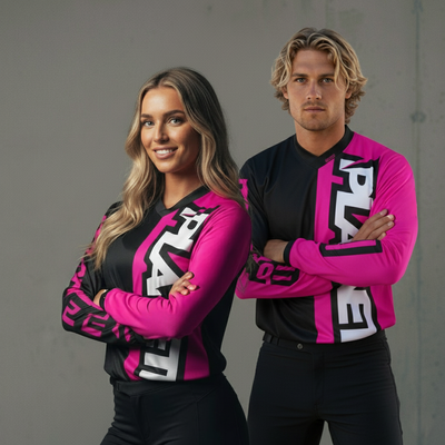 Two individuals wearing matching long-sleeved athletic shirts with black and hot pink panels.