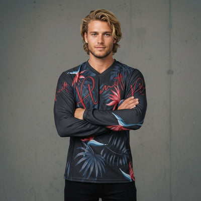 A man wearing a long-sleeved dark gray shirt with red, blue, and black tropical leaf patterns.