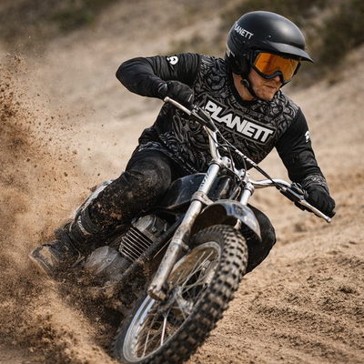 Black and silver vintage-style dirt bike with knobby tires, riding through a dusty track.