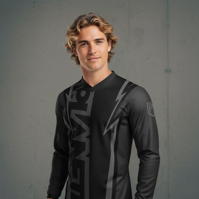A young man with wavy blonde hair wearing a black long-sleeved athletic shirt with gray lightning bolt and vertical stripe designs.