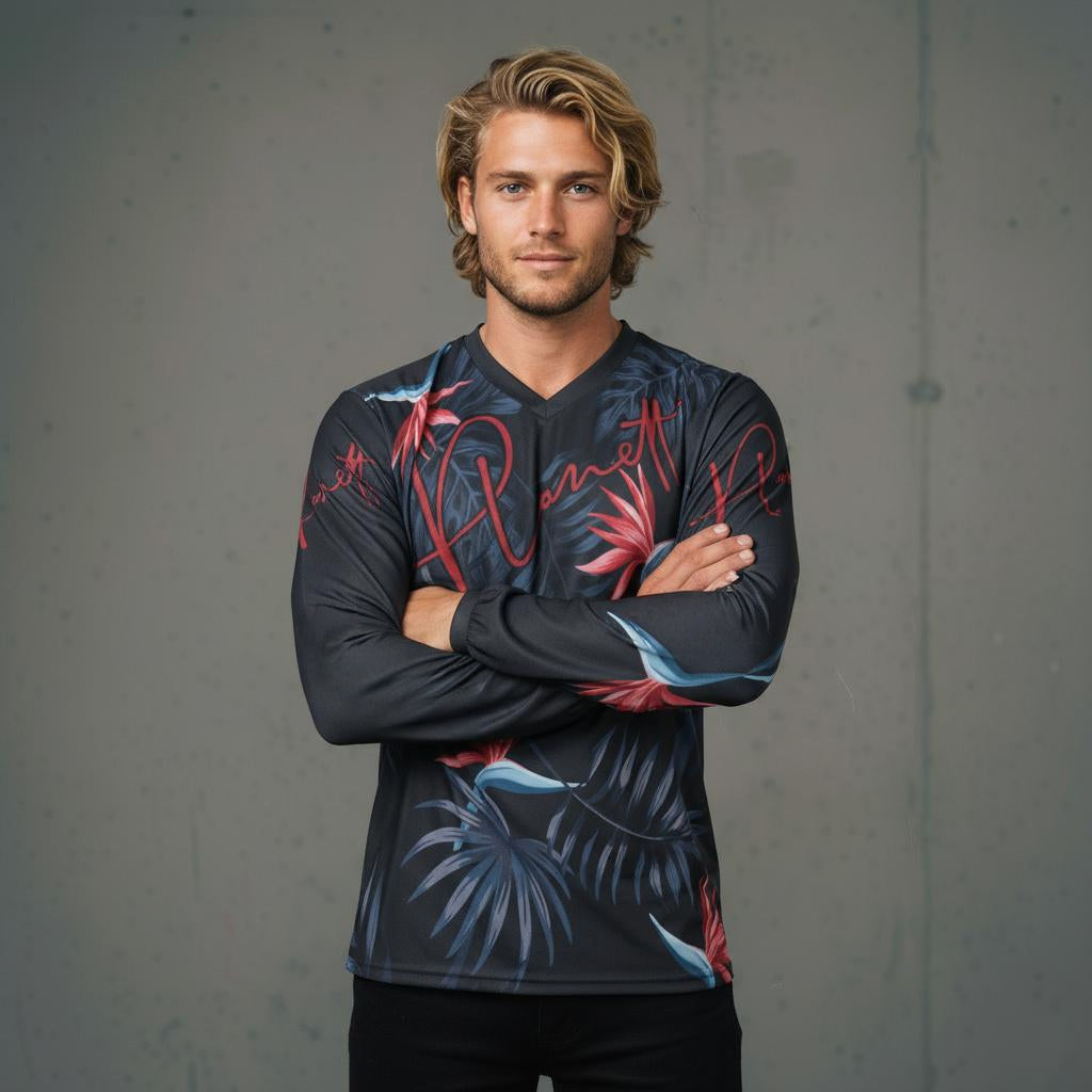 A man wearing a long-sleeved dark gray shirt with red, blue, and black tropical leaf patterns.