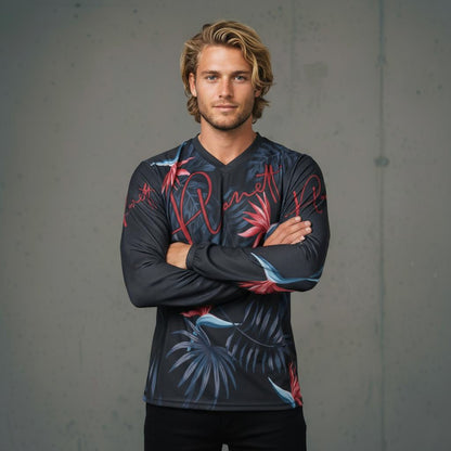 A man wearing a long-sleeved dark gray shirt with red, blue, and black tropical leaf patterns.