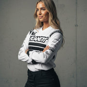 A woman wearing a white long-sleeved athletic jersey and black pants.