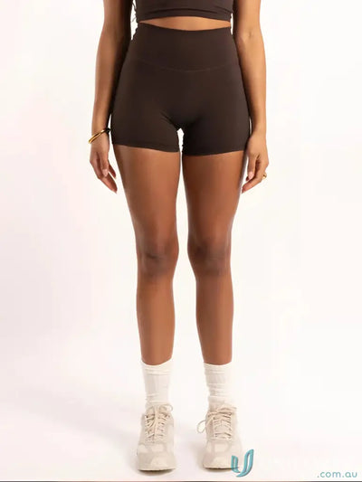 Brown high-waisted shorts with white socks and chunky sneakers.
