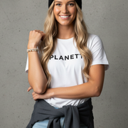 Blonde woman in a black beanie, white T-shirt, and light blue jeans with a dark gray sweatshirt tied around her waist.