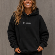 Woman wearing a black hoodie with 'planet' text against a gray background