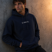 Man wearing a dark blue hoodie with 'planet.' text against a textured wall.