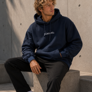Person wearing a navy hoodie with 'planet' logo, sitting on concrete steps.