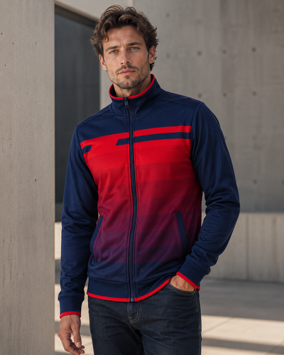 Man wearing a red and blue jacket standing against a concrete wall.
