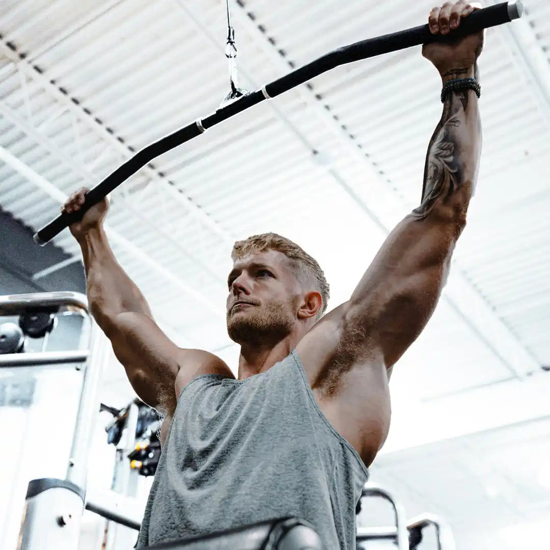 Muscular man using lat pulldown machine.