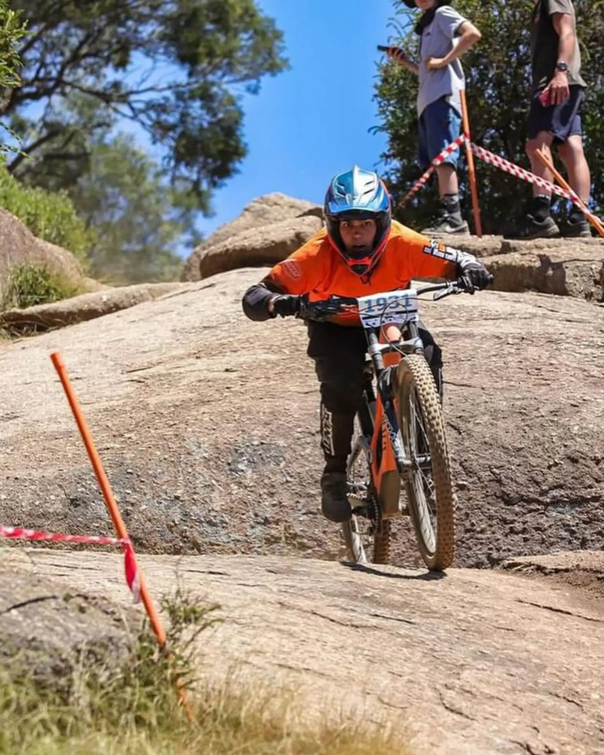 Orange mountain bike with knobby tires and a white race number plate