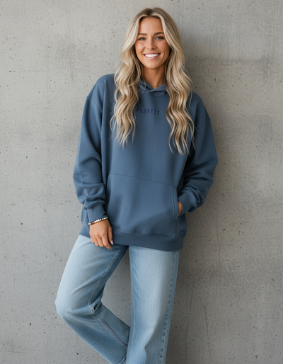A woman wearing a relaxed-fit blue hoodie and light-wash jeans.