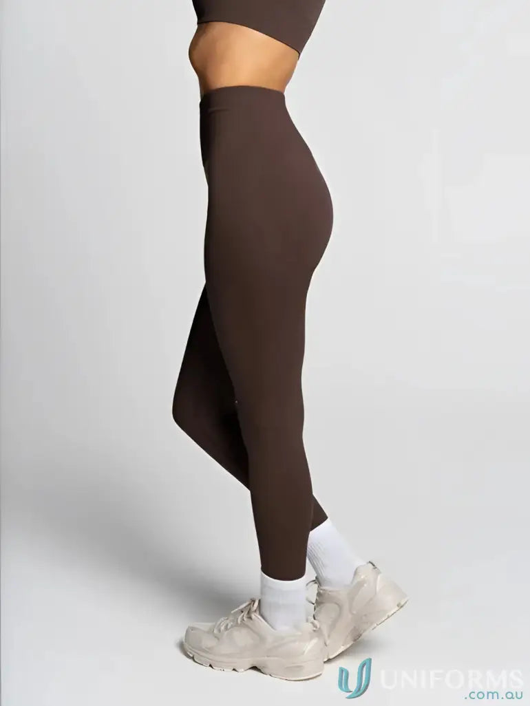 Brown high-waisted leggings with a side slit design and white sneakers.