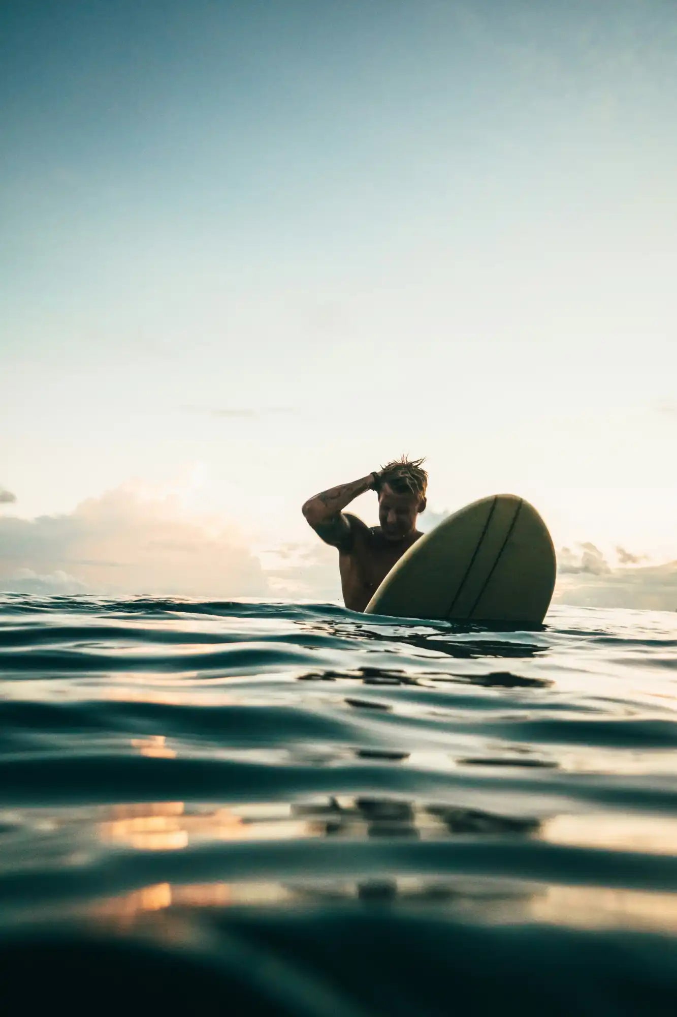 Surfer with surfboard in ocean.