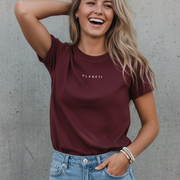 A woman wearing a maroon t-shirt and light blue jeans.