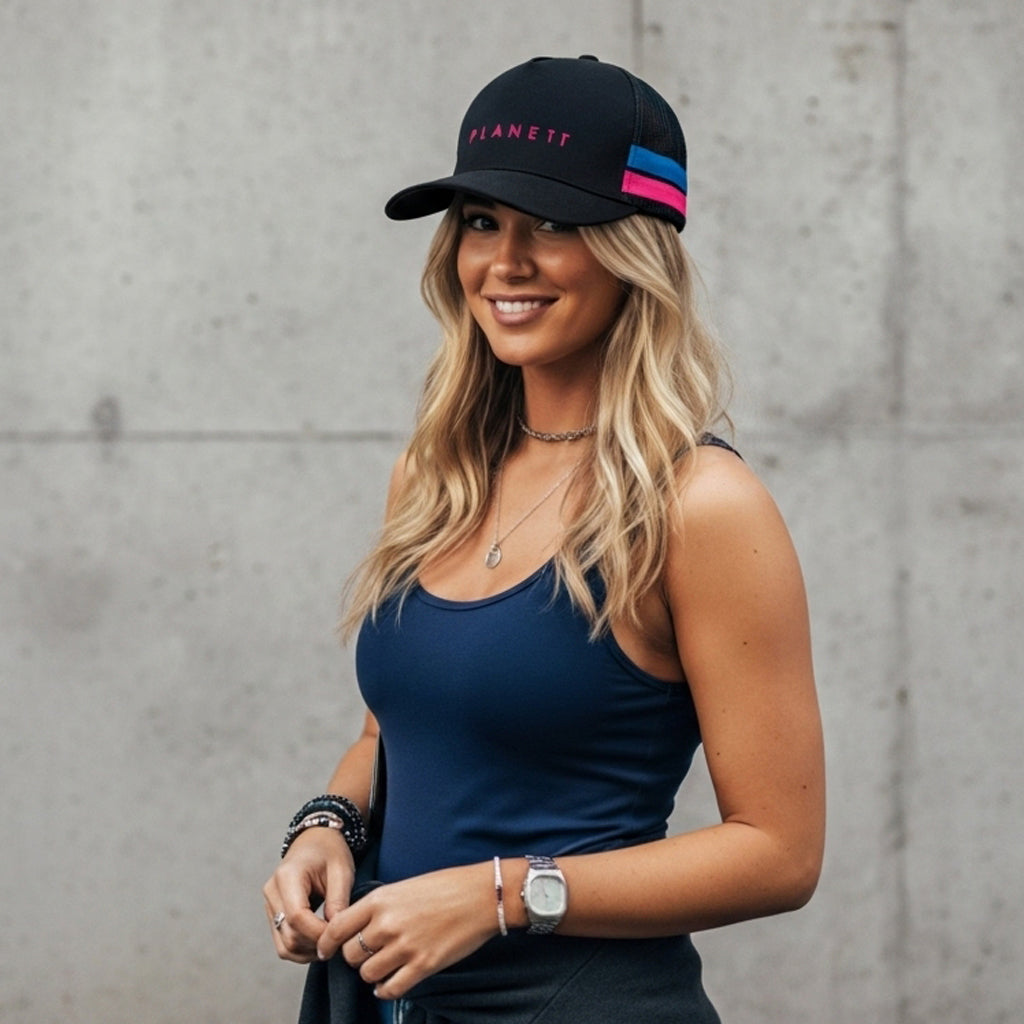 Woman in a black baseball cap and navy blue tank top.