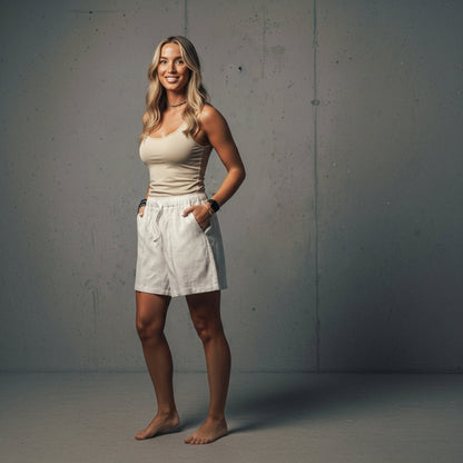 A woman in a beige tank top and white shorts.