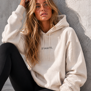 Woman wearing a white hoodie with 'Planet' text, sitting against a gray wall.